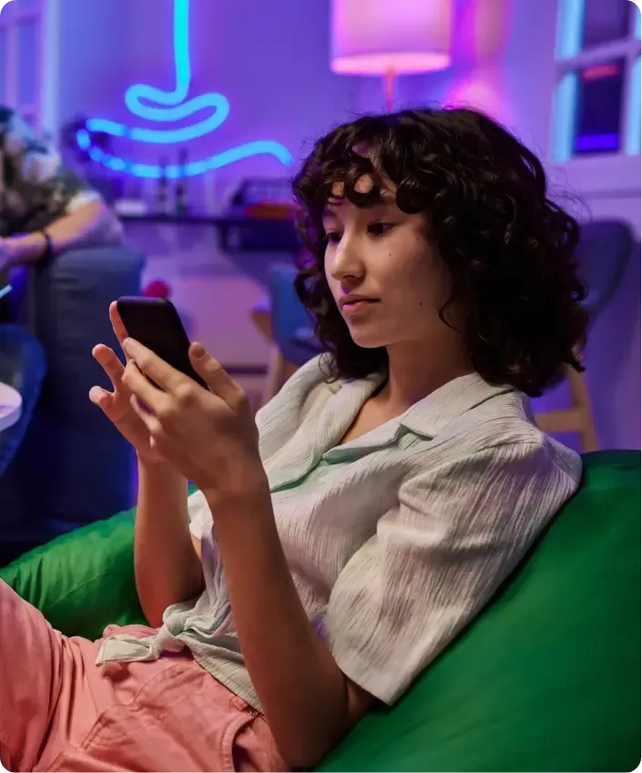 Una donna è seduta su un divano e guarda il telefono.