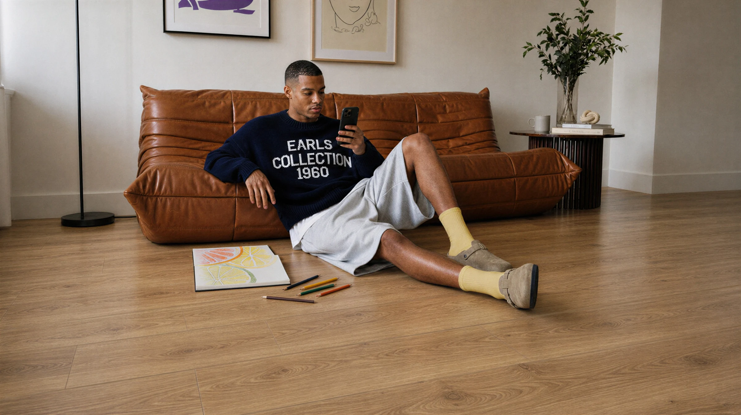 A man looking at his phone while laying on a floor laid out with 91KN732 model kiwi now floor panels